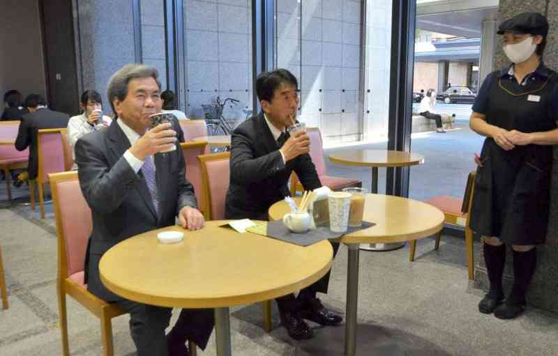 県産牛乳の消費拡大をアピールするため、カフェラテを飲む蒲島郁夫知事（左）＝15日、県庁