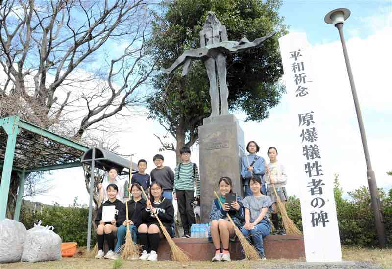 「原爆犠牲者の碑」の清掃に取り組む黒髪小6年の児童ら＝熊本市中央区