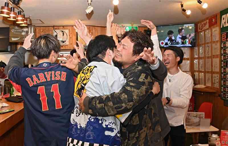 WBC準決勝で、日本代表の村上宗隆選手が逆転サヨナラ打を放ち、抱き合って喜ぶテレビ観戦客＝21日午前11時45分ごろ、熊本市中央区のゴーゴーバー（石本智）