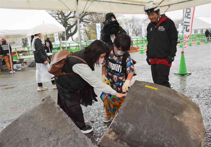 石工が割った巨石の断面を触る親子＝21日、熊本市中央区