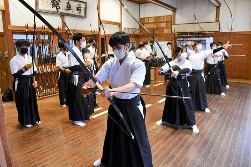 東稜高弓道場での練習では、後ろには順番を待つ部員たちが並んだ＝3月16日、熊本市東区
