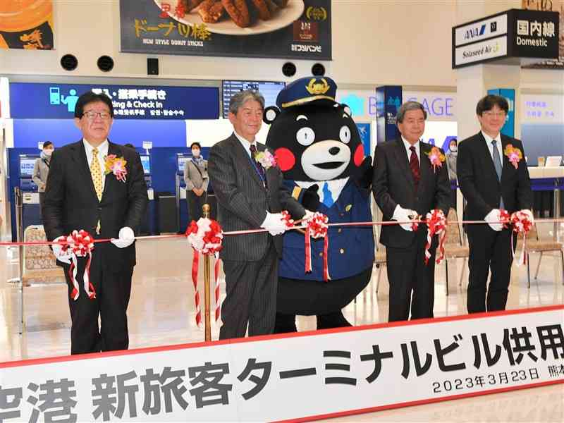 熊本空港の新しい旅客ターミナルビルの開業を祝い、テープカットする熊本国際空港の新原昇平社長（左から2人目）ら＝23日午前6時30分、益城町（鹿本成人）