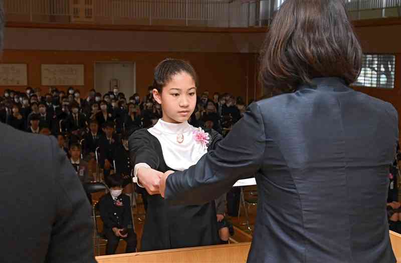 日吉東小の卒業式で、池田由美校長（手前）から卒業証書を受け取る6年生児童＝23日午前、熊本市南区（石本智）