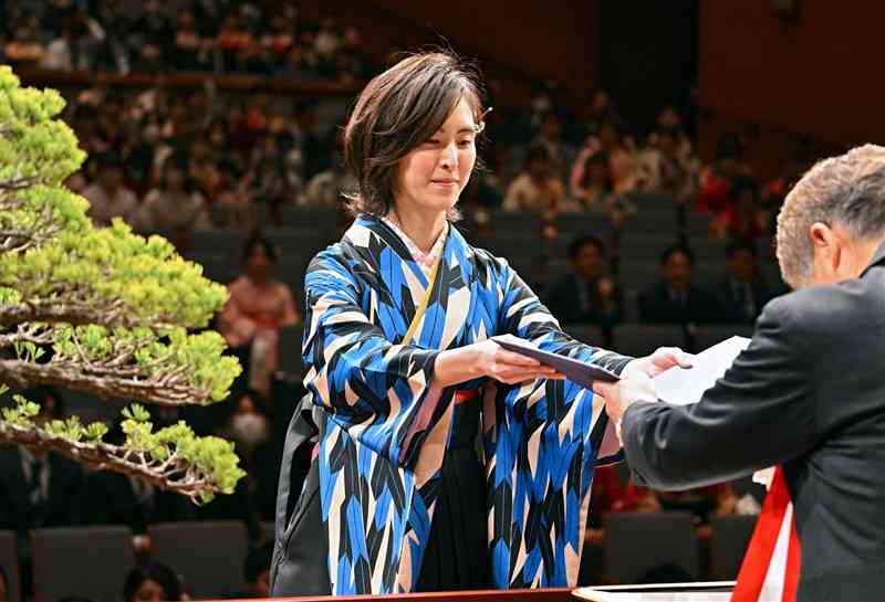 熊本大の卒業式で、小川久雄学長（右）から学位記を授与される文学部4年の水谷はつのさん＝25日午前、熊本市中央区の県立劇場（鹿本成人）