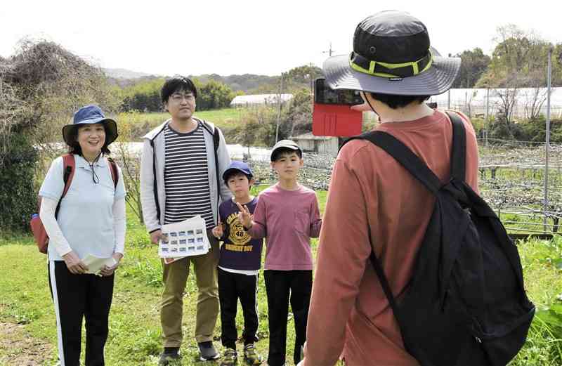 チェックポイントのナシ園を背に写真を撮る参加者＝荒尾市