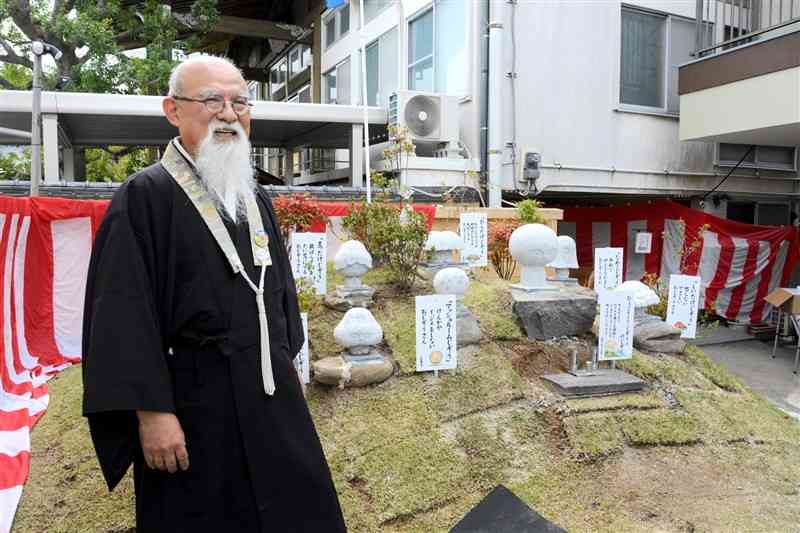 駐車場に登場した「ひょっこり山」と濱田智海住職＝水俣市