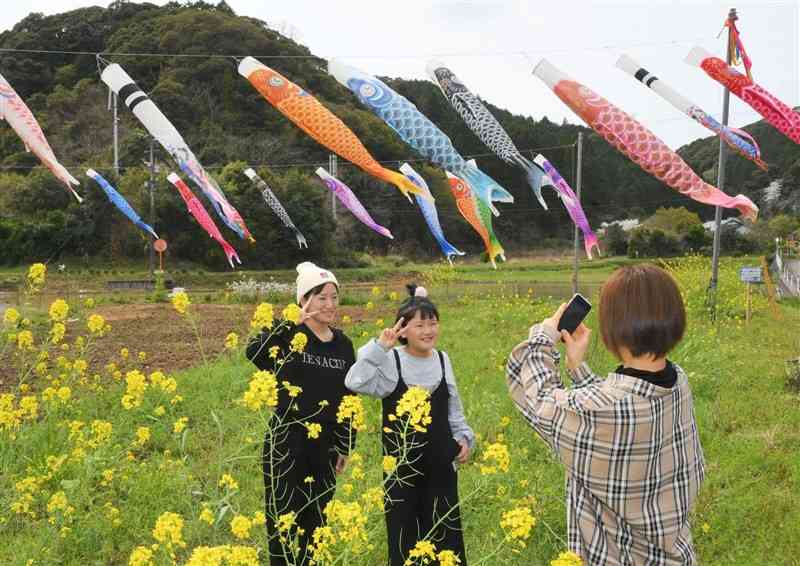 こいのぼりと菜の花をバックに記念撮影する中さん親子＝天草市