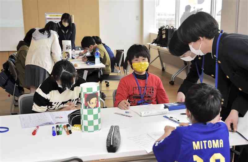 高校生のアドバイスを受けながら課題に取り組む小学生＝荒尾市