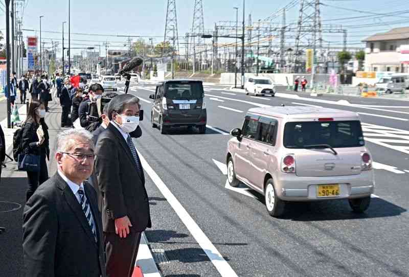 県道熊本高森線の4車線化の一部供用が始まり、通行する車を見送る蒲島郁夫知事（手前から2人目）ら＝28日午後、益城町（谷川剛）