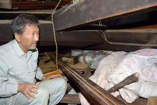 全壊した自宅で、長女の恵美さんが梁に挟まれた場所を示す前田義弘さん＝嘉島町下六嘉
