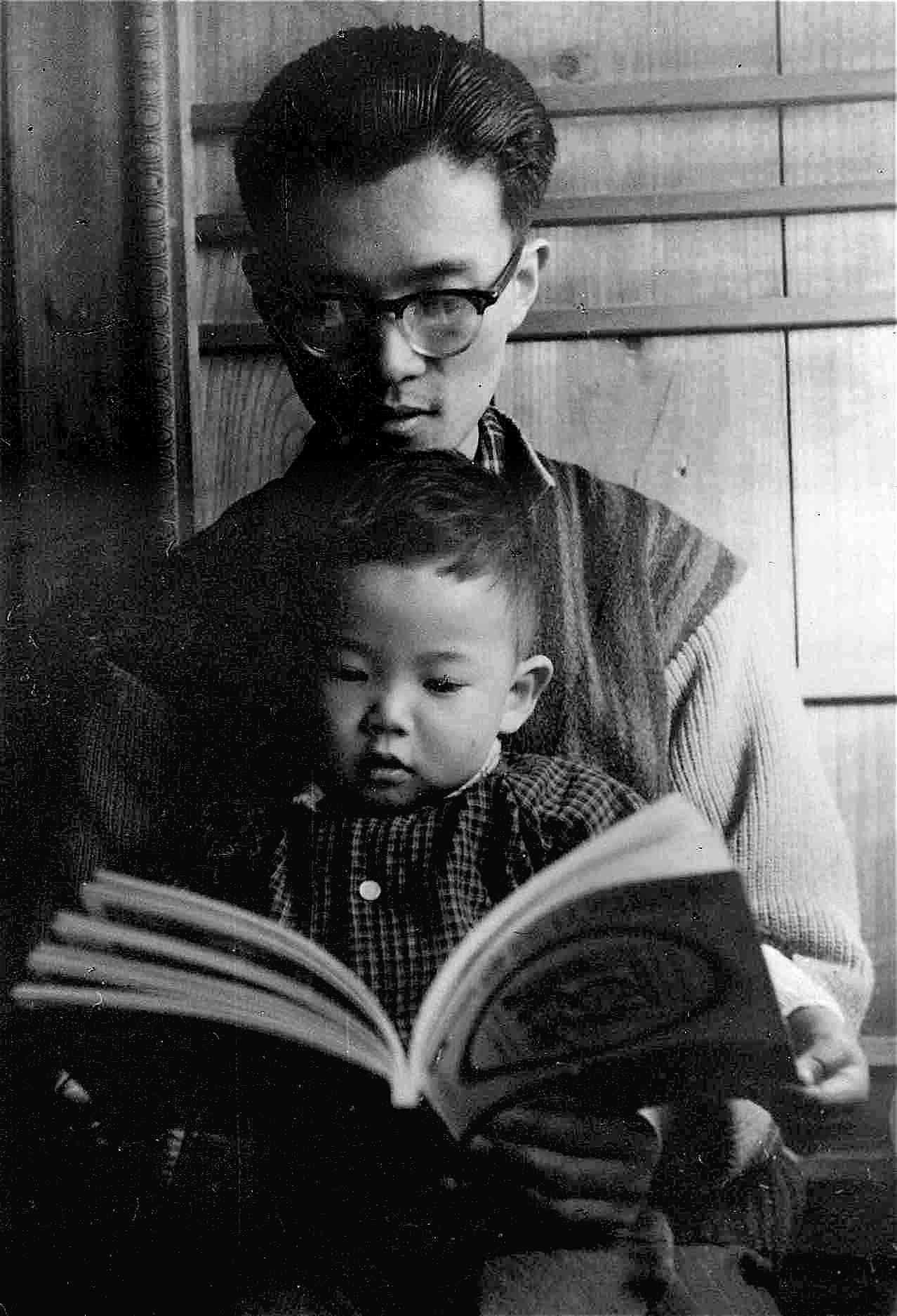 自宅押し入れ前で父親に本を読んでもらっている筆者（1961年頃）
