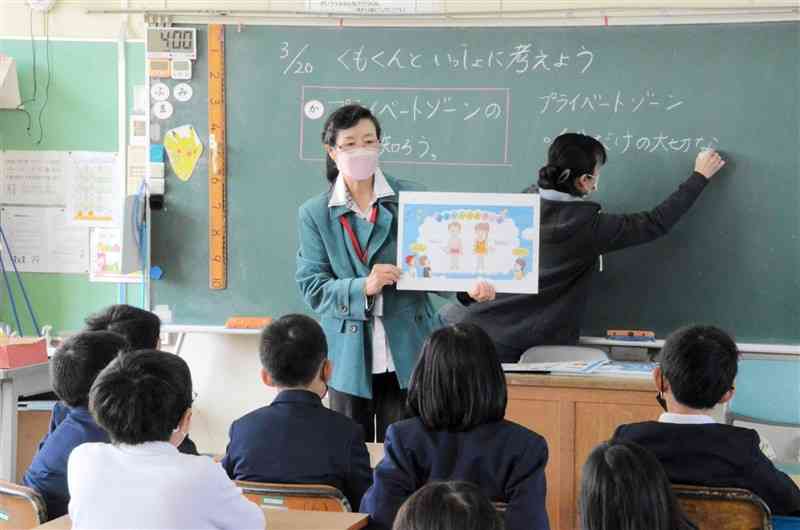 紙芝居でプライベートゾーンの大切さを児童に伝える天草人権擁護委員協議会長の櫻田京子さん＝天草市