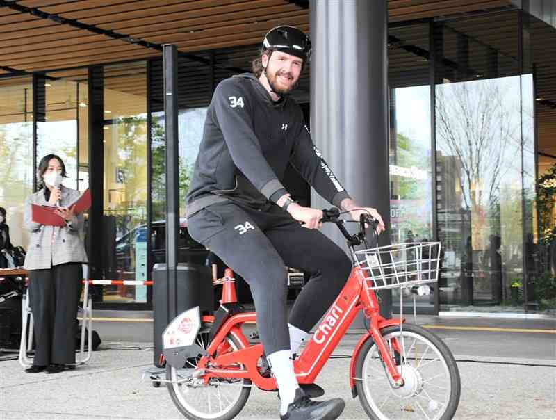 「チャリチャリ」の自転車に乗って利用をPRするベンジャミン・ローソン選手＝5日、熊本市