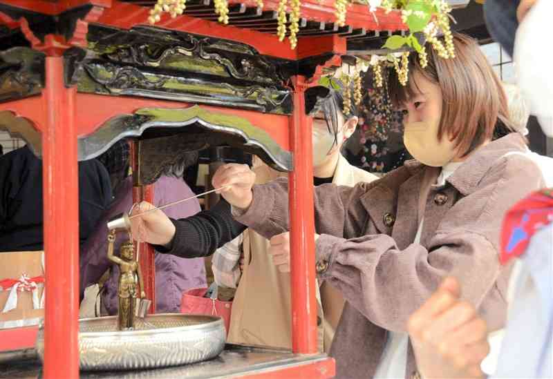 釈迦院で花御堂に置かれた仏像にひしゃくで甘茶をかける参拝者＝八代市泉町