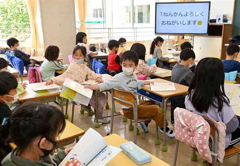 始業式後、新しいクラスで新学年の教科書を配る児童たち＝10日午前10時50分ごろ、熊本市東区の月出小（石本智）