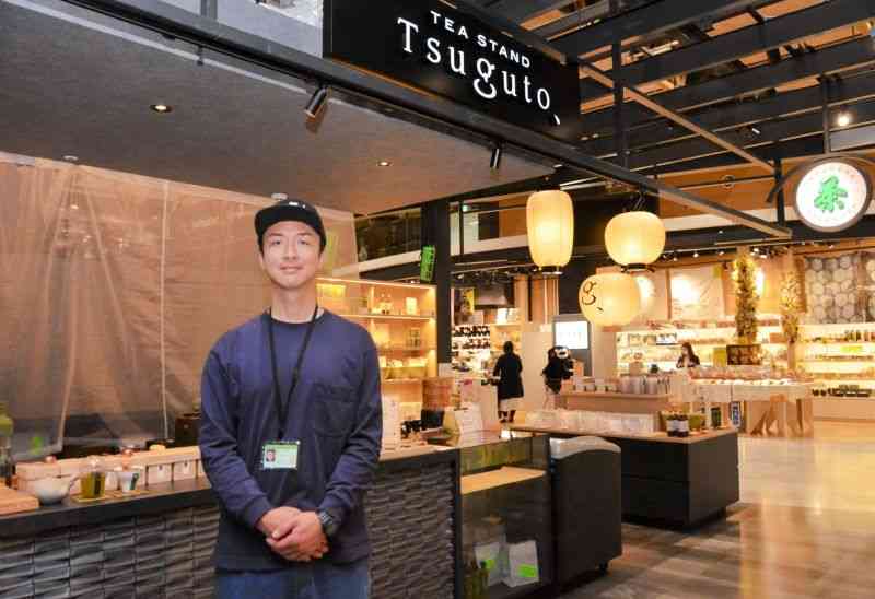 熊本空港の新旅客ターミナルビルにオープンした「Tsuguto」の店頭に立つ富澤堅仁さん＝益城町