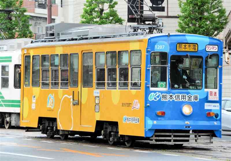 熊本信用金庫の創立100周年を記念して運行を始めたラッピング電車＝熊本市中央区