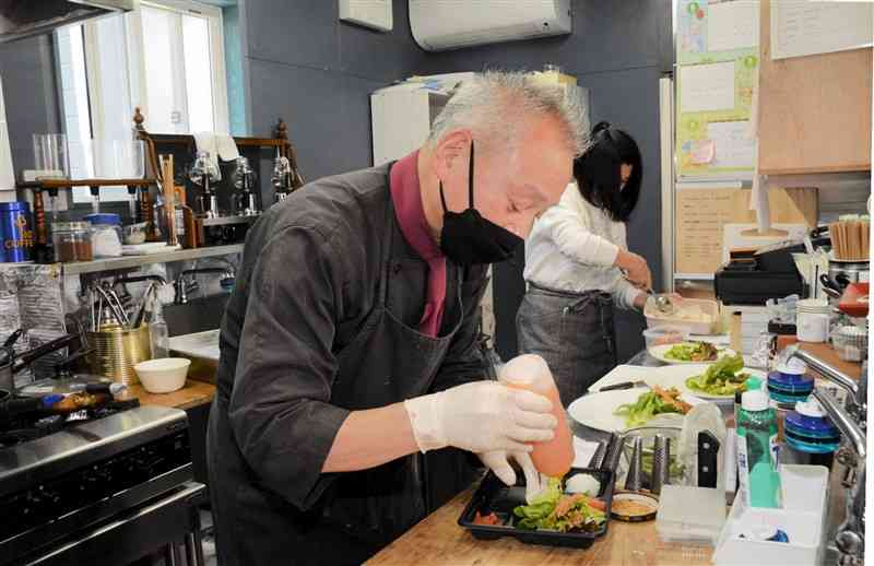 「Cafeしもん」で、料理を盛りつける桐原研二さん＝合志市