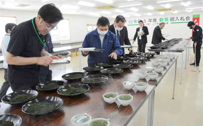県産一番茶の初入札会で、茶葉の香りや柔らかさを確かめる販売業者ら＝18日、益城町