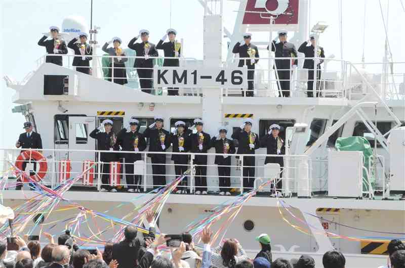 出港する「熊本丸」の甲板から、見送りの人たちに敬礼する天草拓心高の生徒ら＝苓北町