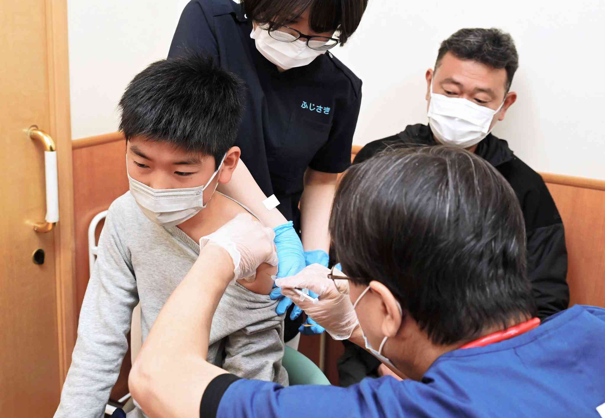 保護者（右奥）同伴で新型コロナウイルスワクチンの接種を受ける子ども＝７日、宇城市のうちの小児科小児外科（池田祐介）