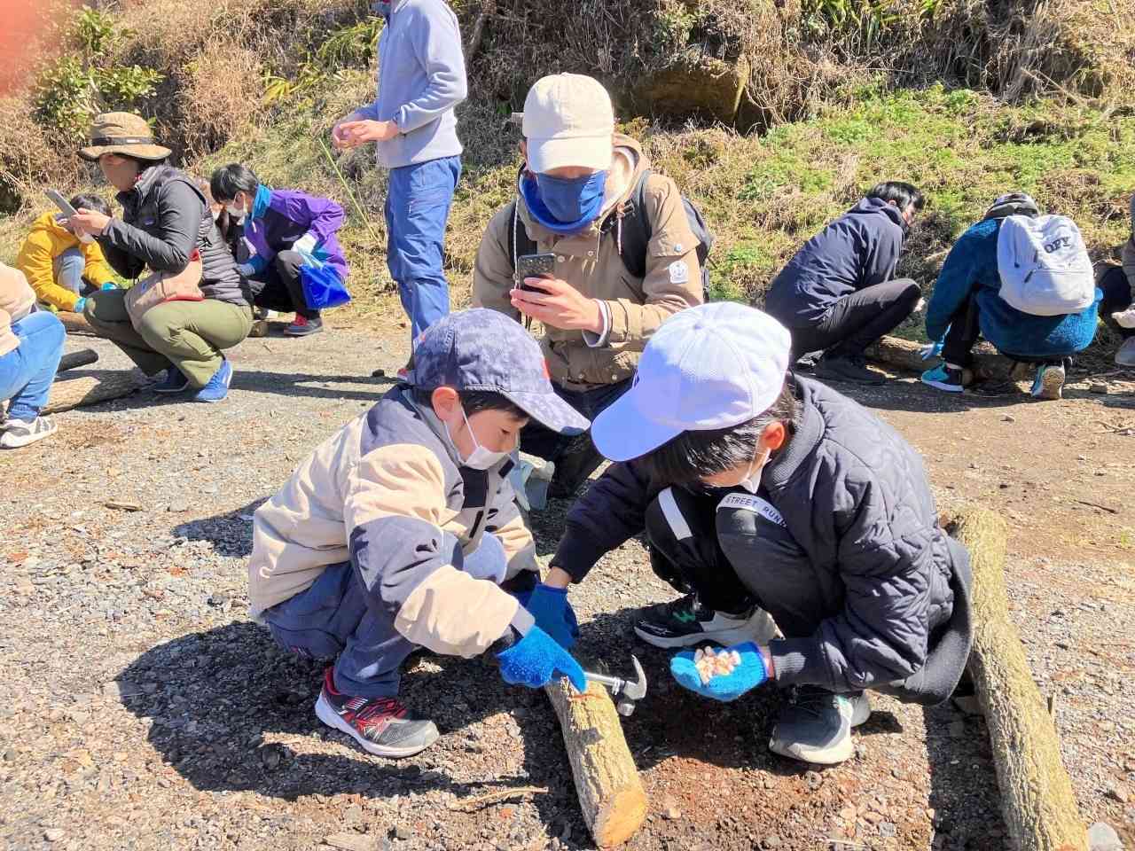 シイタケの駒打ちを体験するくまTOMOサポーターたち＝2月下旬、高森町下切地区