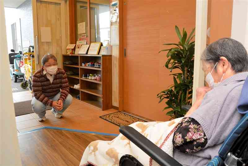 有料老人ホーム「まごころの家」で、入所する母親（右）と距離を保って面会する佐藤民雄さん＝4月下旬、熊本市北区