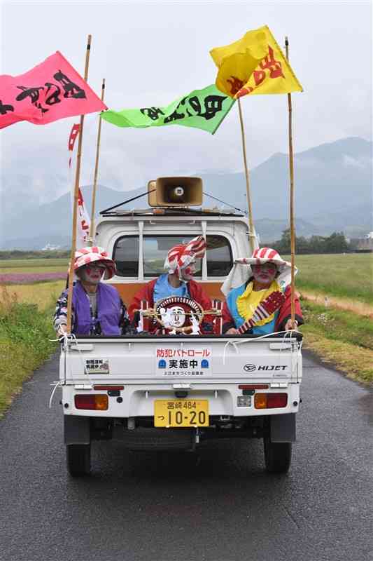 田の神さあを軽トラックの中央に乗せ、農道をパレードする末永地区の住民たち＝えびの市