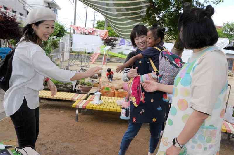 保護者に見送られ、元気に登園する幼稚園児。新型コロナウイルスの「5類」移行を受け、登園時の検温や職員のマスク着用をやめた＝8日、熊本市中央区