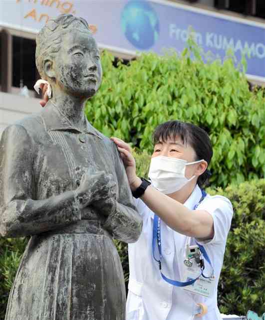 「赤十字看護婦像」を拭き上げる上野珠美さん＝熊本市東区