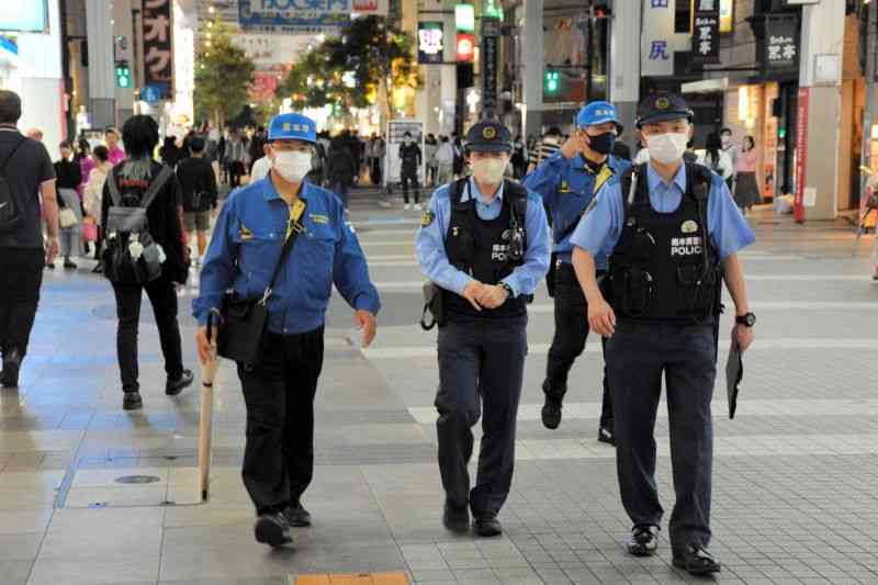 中心繁華街を歩き、客引きに目を光らせる熊本市の巡回指導員と警察官＝12日午後9時ごろ、同市中央区