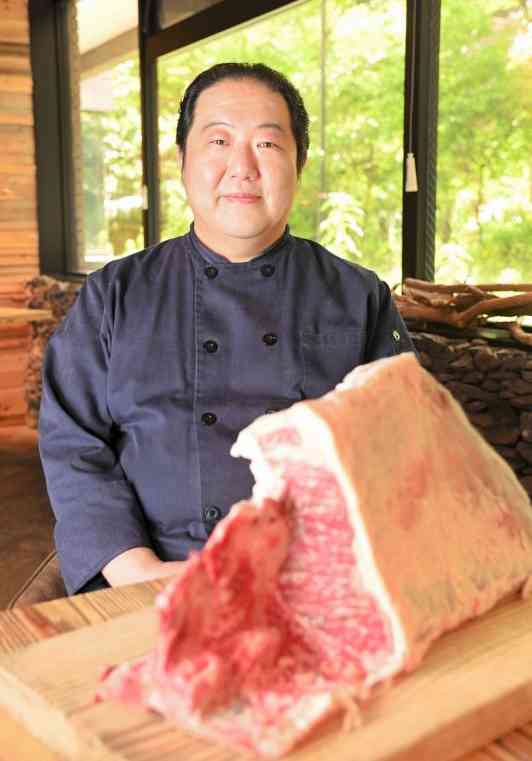 経営するレストランで、阿蘇の草原で放牧肥育したあか牛の肉を披露する宮本健真さん。「まきで焼いたステーキは最高ですよ」と語る＝17日、熊本市