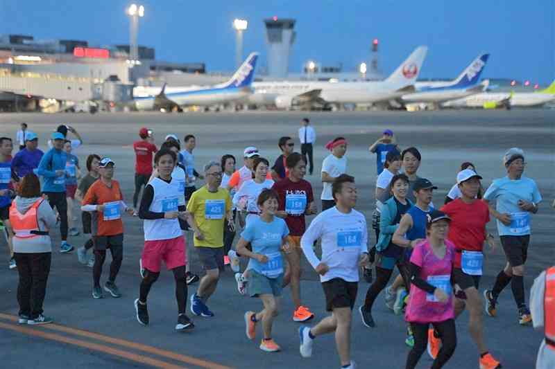 熊本空港マラソンで、駐機された飛行機を背に走るランナーたち＝27日午前4時50分ごろ、熊本空港（上杉勇太）