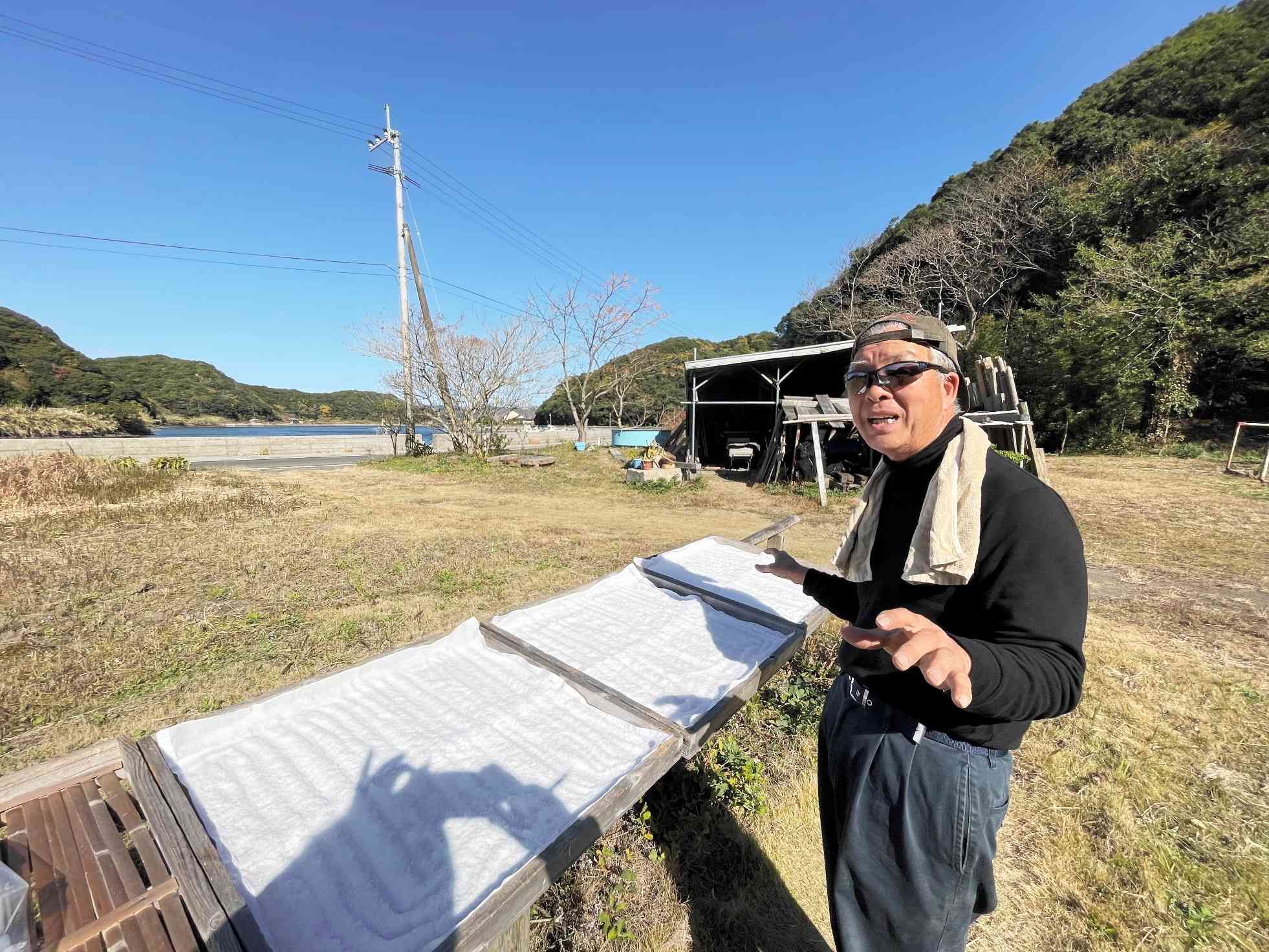 天草の海から作った塩を天日干しする戸谷泰典さん＝昨年１２月、天草市