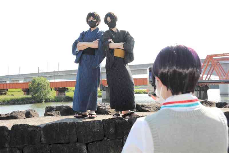 加勢川や鉄道橋を背景に写真撮影するコスプレーヤー＝熊本市南区