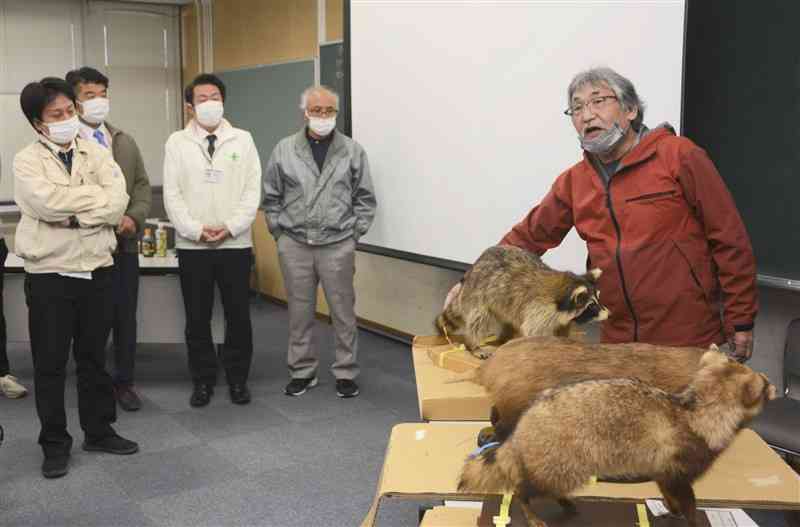 自治体や農協の職員たちに、アライグマ防除の必要性を訴えるNPO法人・くまもと未来ネットの歌岡宏信さん（右端）＝熊本市北区役所