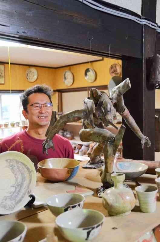 マンガやアニメが好きという上村慶次郎さん。趣味でエヴァンゲリオンやガンダムなどのフィギュア（非売品）も陶器で制作している＝八代市坂本町