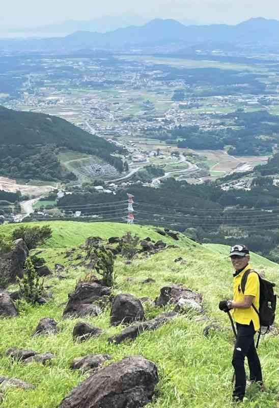 遠く島原方面まで見通せる絶景ポイントに立つ松尾俊さん