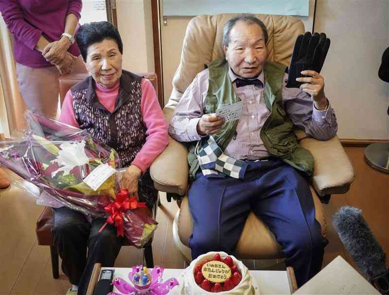 87歳の誕生日（たんじょうび）にプレゼントのてぶくろを持つ袴田巌さん。左は、袴田さんをささえ続けてきた姉のひで子さん＝3月、静岡県浜松（はままつ）市