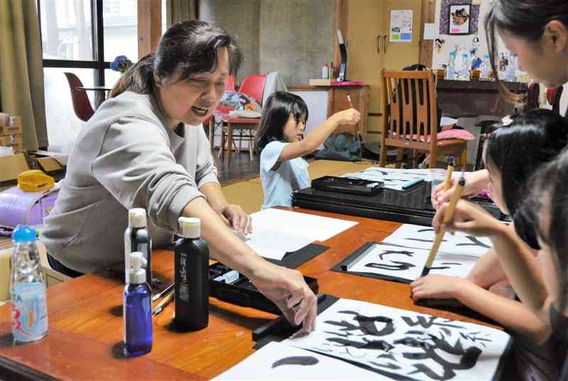 「だんだんほーむICOCA」を訪れた子どもたちに書道を教える嘉島町議の穴井智子さん＝6日、嘉島町