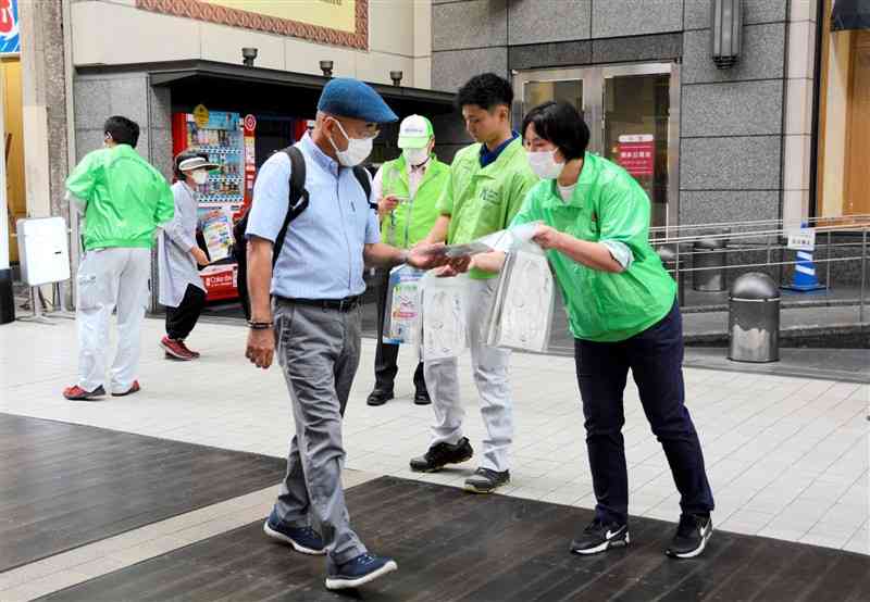 通行人に啓発チラシを手渡す「ロックの日」防犯キャンペーンの参加者（右）＝9日正午過ぎ、熊本市中央区