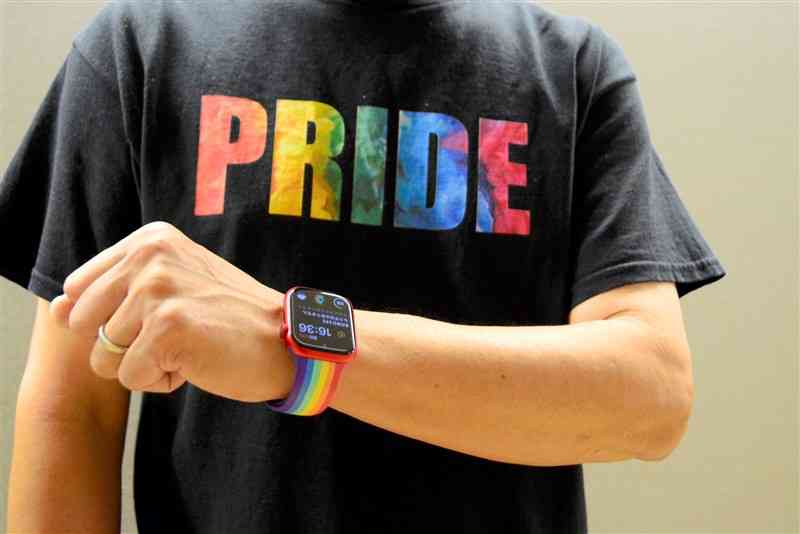 同性婚訴訟の福岡地裁判決公判で、レインボーカラーの時計バンドやTシャツを着用して傍聴席に入った男性。文字を隠し、時計は外すよう指示された＝8日、福岡市