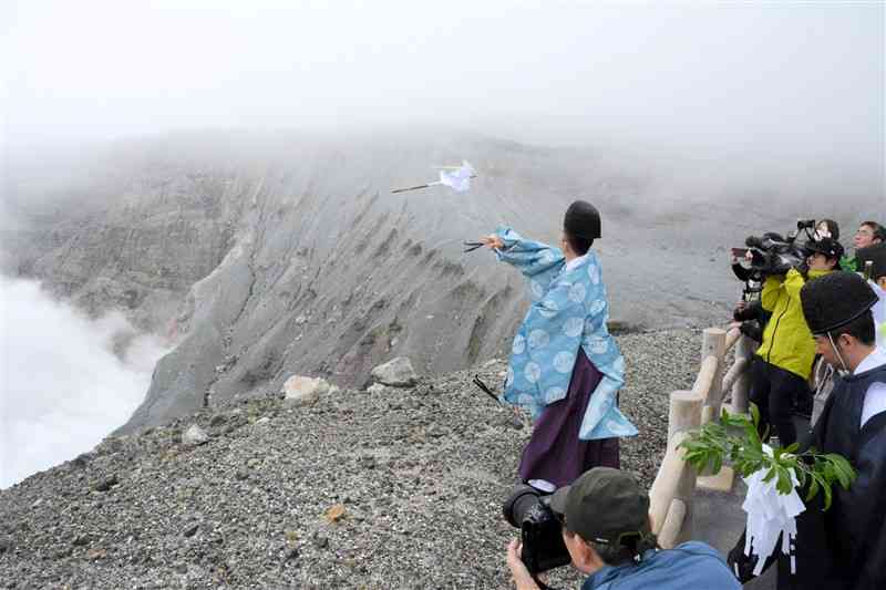 阿蘇中岳第1火口に向かって御幣を投げ入れる阿蘇神社の阿蘇惟邑宮司＝阿蘇市