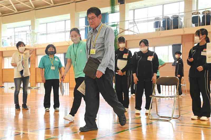 高齢者の歩行速度を測定する熊本保健科学大の学生や阿蘇中央高の生徒ら＝阿蘇市