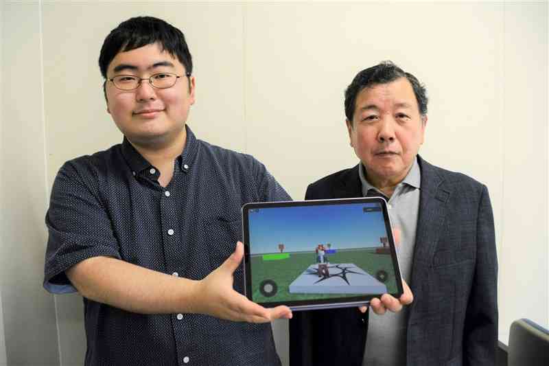 幼児向けのメタバース（仮想空間）ゲームを制作した下田眞聡さん（左）と指導した境章さん＝熊本市中央区