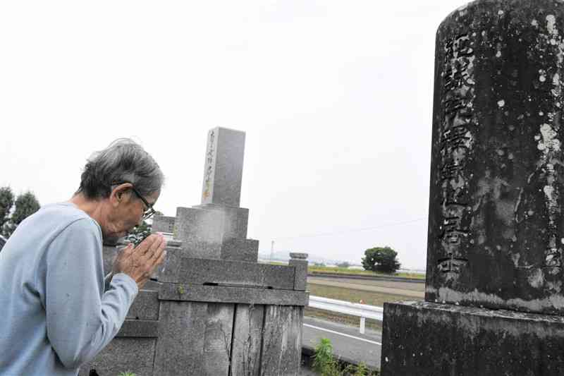 自宅そばの荒木克業大尉の墓に参る林田忠昭さん。墓には陸軍からの「感状」の内容も記されている＝14日、熊本市南区