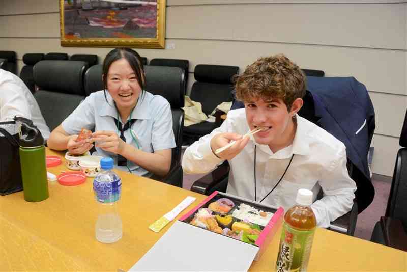 米サンアントニオ市の高校生（右）と弁当を食べる必由館高生＝熊本市中央区