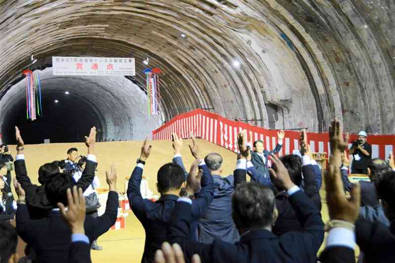 国道57号滝室坂トンネルの貫通を祝って万歳三唱をする出席者ら＝阿蘇市