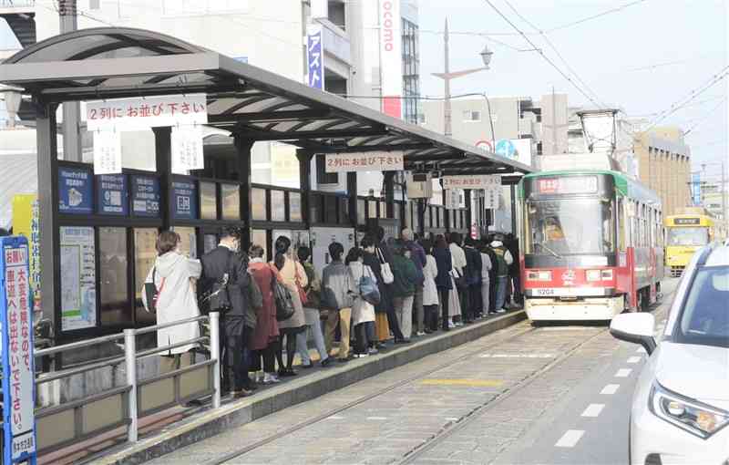 通勤通学客が並ぶ熊本市電の健軍町電停。電停から手前に向かって市民病院までの延伸が計画されている＝同市東区、3月30日