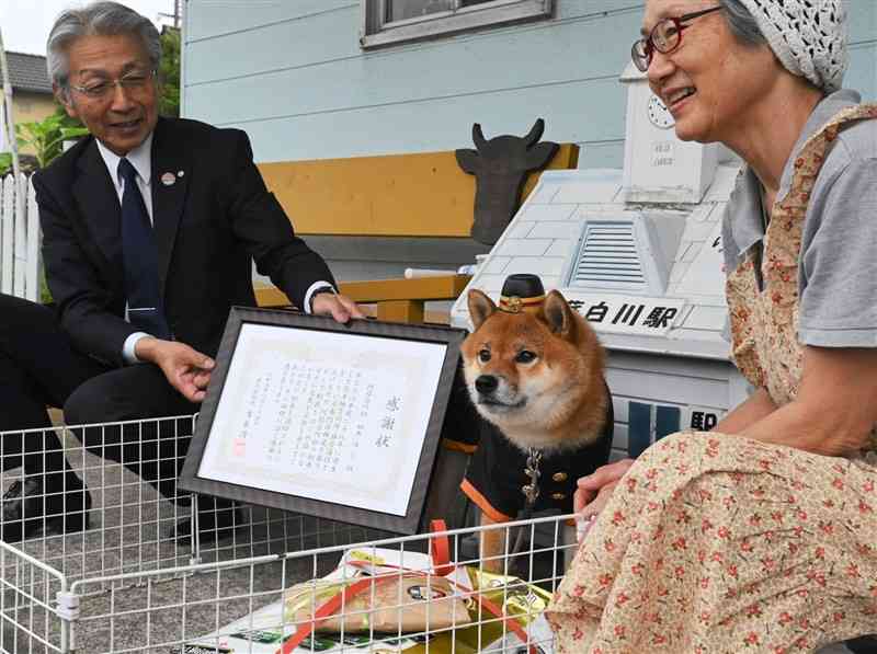 吉良清一村長（左）から感謝状を贈られる柴犬の「ゆう」＝南阿蘇村
